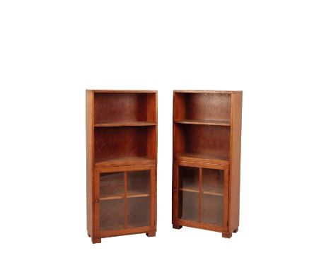 HEAL AND SONS: A PAIR OF OAK BOOKCASES, rectangular form, two open-shelves, below a cupboard with hinged glass door, with sin