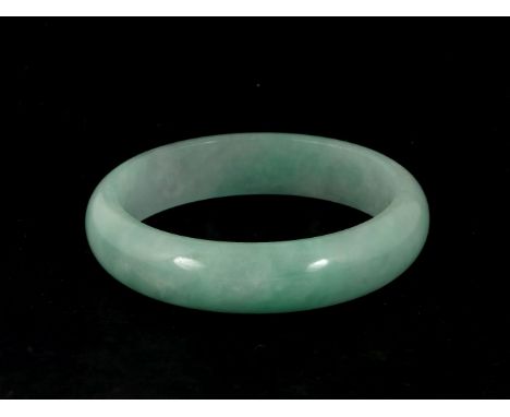 A jade bangle, 20th century, of even pale green, 7.2cm diameter