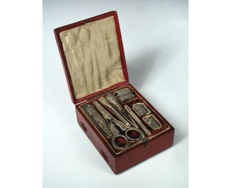 A late 19th century Continental red leather clad nécessaire case, the rectangular cover opening to reveal a set of eight unma
