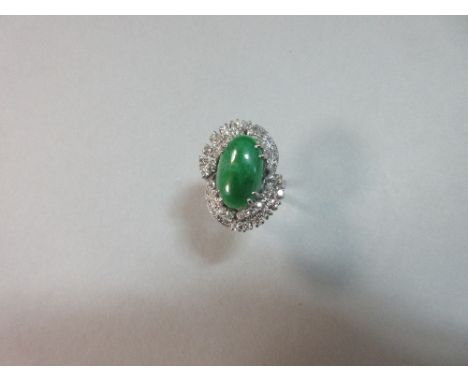 A jade and diamond ring, the oval cabochon opaque green jade claw set in an open double swirl of single cut diamonds to a wir