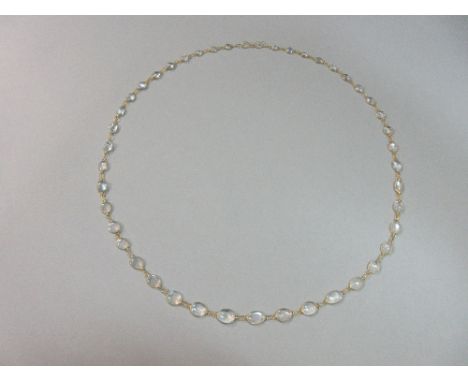 A modern moonstone rivière necklace, formed by a graduated line of oval cabochon moonstones spectacle set and separated by fi