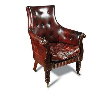 A Regency mahogany library armchair, upholstered in buttoned dark red leather, with squab seat cushion, reeded show wood, out