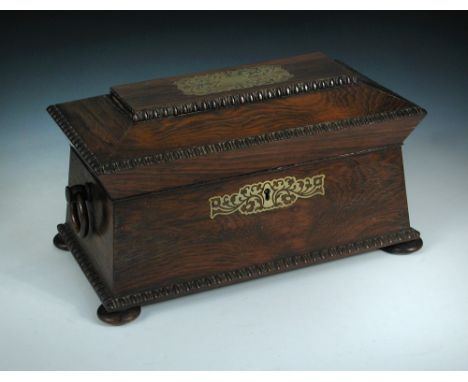 A Regency rosewood sarcophagus tea caddy, with brass inlays and gadrooned edges, ring turned handles to either side and raise