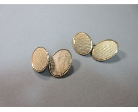 A pair of 9ct gold double-ended cufflinks, each oval end with engine-turned patterning, chain connections, Chester import hal