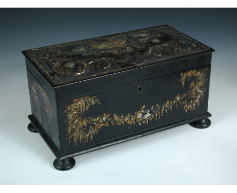 A late Regency papier maché tea caddy, the hinged cover opening to reveal a central glass bowl flanked by tea compartments to