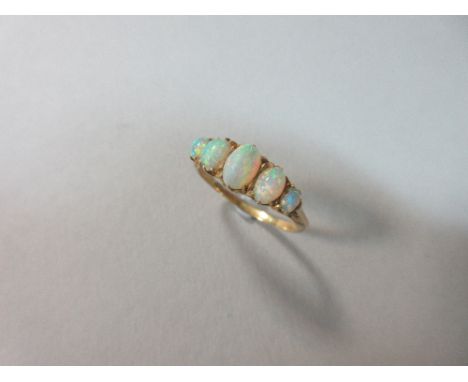 An Edwardian five stone opal ring, the graduated oval cabochon opals claw set above a pierced scrolling gallery and shoulders