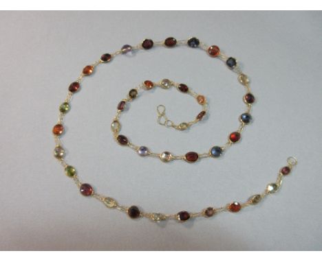 A contemporary multi-gem necklace, composed of a graduated line of spectacle set oval and round cut gemstones in saturated sh