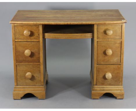 An oak bow-front knee-hole desk fitted with an arrangement of six drawers, &amp; on bracket feet, 40” wide x 29” high x 22” d