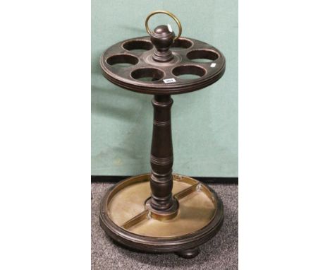 19th century ebonised spindle stick stand with six circular apertures raised on turned column, complete with brass drip trays