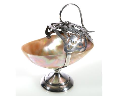 Silver mounted mother-of-pearl table salt, the pierced basket support with scroll handle, raised on a socle base, B T Greenin