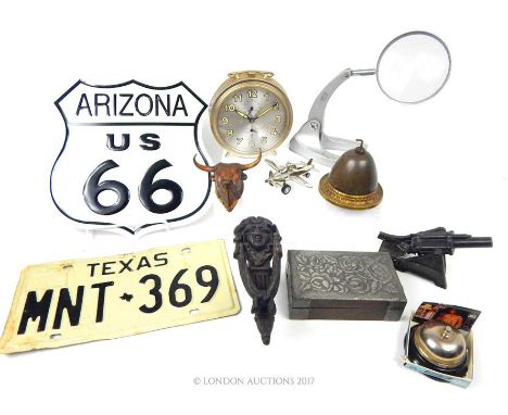 A magnifying glass on a stand, a model of a Howitzer, a Texan number plate, and other items.