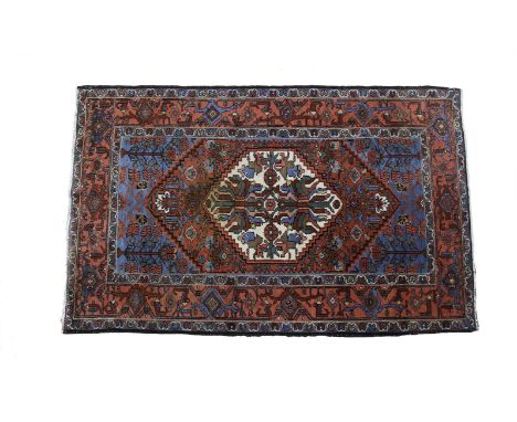 A SEMI-ANTIQUE JOSHAGAN WOOL RUG, the red and blue ground centred with a large ivory ground foliated medallion within multipl