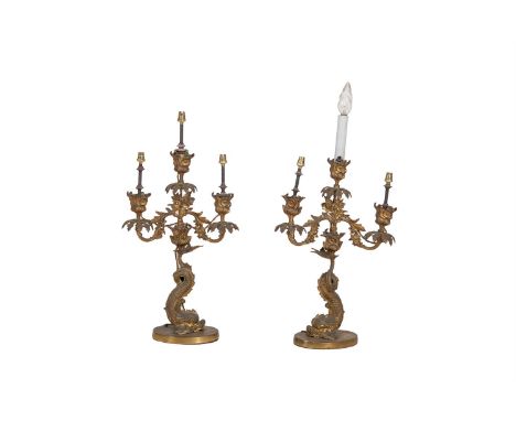 A PAIR OF BRASS CAST THREE LIGHT CANDELABRA on dolphin supports, 50cm tall