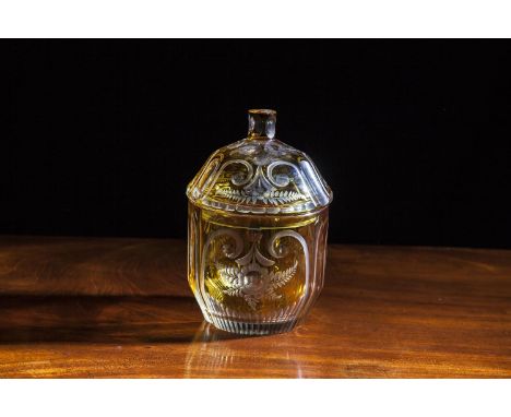 AN AMBER GLASS JAR AND COVER, of circular form with domed lid and shaped cylindrical finial, the entire decorated with wheel 
