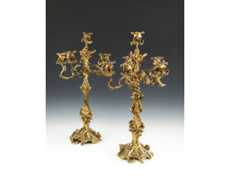 A PAIR OF EARLY 19TH CENTURY FRENCH ORMOLU FIVE LIGHT CANDELABRA, in rococo style, the naturalistic cast sconce and scrolling