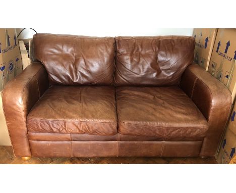Two seater tan coloured leather sofa. Light scratches and light wear to seats and arms, a few light scratches to sides. 