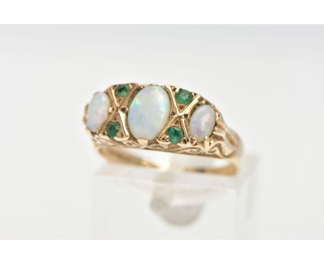 A 9CT GOLD, OPAL AND EMERALD RING, three oval opals set with four small circular cut emeralds, prong set in a raised scroll d