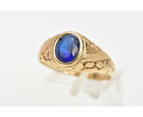 A 9CT GOLD SIGNET RING, set with an oval cut blue paste, bezel set, textured shoulders leading onto a plain polished band, ha