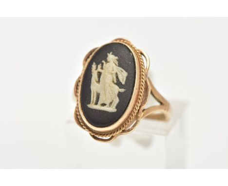 A 9CT GOLD WEDGWOOD RING, of an oval design set with a black and white cameo, bezel set with a rope twist and openwork scallo