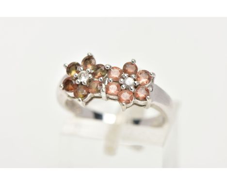 A 9CT WHITE GOLD, GEM SET RING, designed as two flowers set with a central colourless stone each in a surround of circular cu