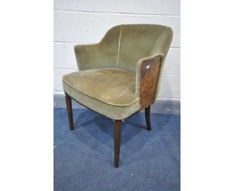 AN ART DECO ARMCHAIR, covered in green velour upholstery, with burr walnut panel to outer front edge of armrest, on tapered o