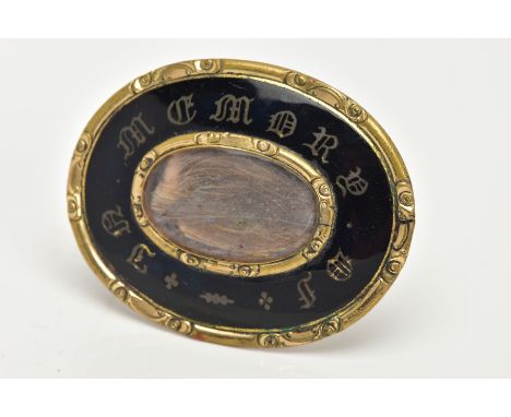 A VICTORIAN MOURNING BROOCH, an oval yellow metal brooch, black enamel with gold writing 'IN MEMORY OF', oval glass pane enca