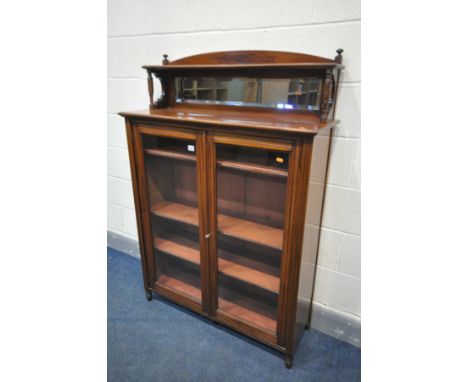 AN EDWARDIAN WALNUT BOOKCASE, with a raised mirrored shelf back, over double glazed doors, enclosing three adjustable shelves