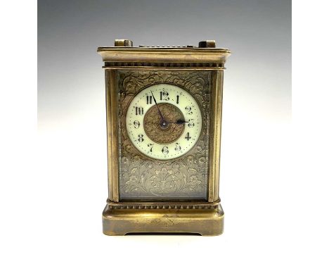 A late 19th century French brass carriage timepiece with Arabic numerals on an enamel ring face with an embossed foliate scro