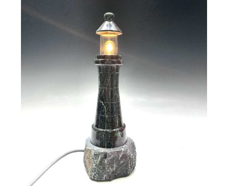 A Cornish turned serpentine lighthouse lamp, with glass canopy and of waisted form with rocky base, height 35cm.No condition 