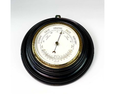 A late Victorian aneroid circular barometer, with white ceramic dial and ebonised case, diameter 28cm.