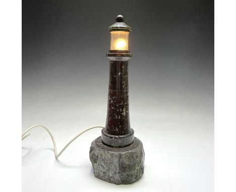 A Cornish serpentine turned lighthouse lamp, with removable glass top and rock base, height 41cm.Chip to the bottom rim of gl