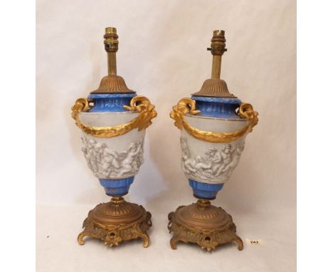 A pair of neo-classical ceramic table lamps decorated in relief with Bacchanalian scenes, gilded, raised on rococo ormolu bas