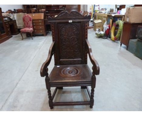 A 17th century joined oak wainscot chair, the back carved with birds and foliage. The seat later adapted as a commode