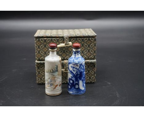 Two Chinese porcelain cylindrical snuff bottles and stoppers,&nbsp;comprising: a blue and white example with four character m