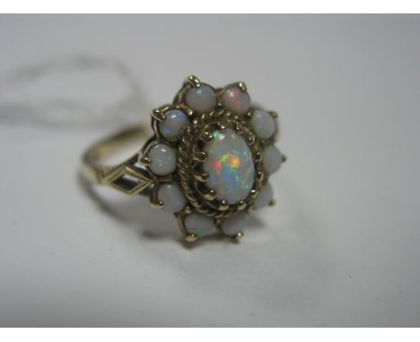 A 9ct Gold and Opal Dress Ring, the principal stone claw set to a rope surround, within a halo of uniform cabochon stones, to