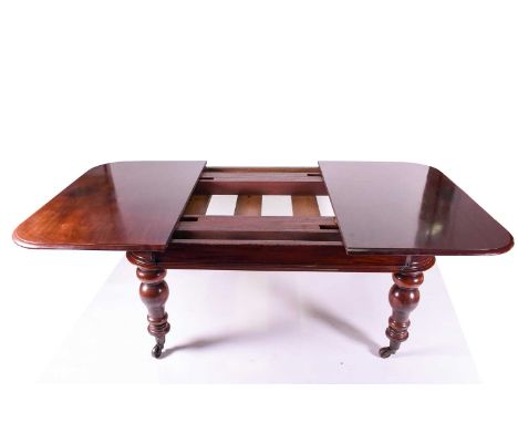 A Victorian mahogany extending dining table, with three leaves, the figured top with moulded edges, supported on turned legs 