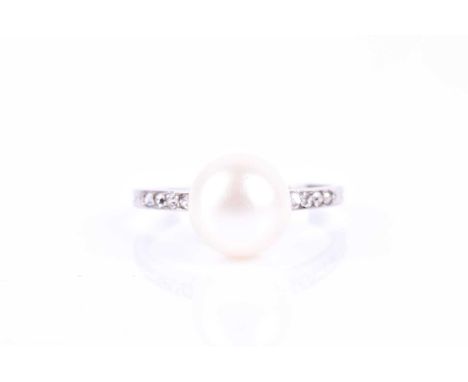 An early to mid 20th century white metal, diamond, and pearl ring, set with a white pearl of approximately 9mm diamete, the s