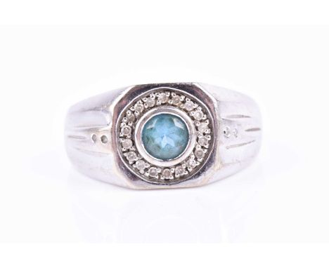 A 9ct white gold and blue topaz gents ring, the squared mount inset with a round-cut stone, within a border of small round-cu