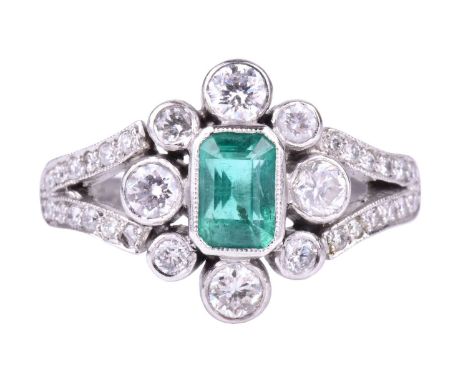 A platinum, diamond, and emerald ringcentred with an emerald-cut emerald of approximately 0.70 carats, within a border of col