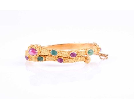 An unusual Eastern yellow metal bangle, in the form of an ornately decorated snake, the head and tail forming the terminals, 