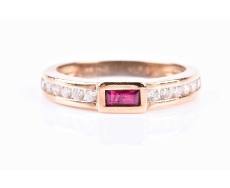An 18ct yellow gold, diamond, and ruby ring, bezel-set with a rectangular-cut ruby, the shoulders channel-set with round-cut 
