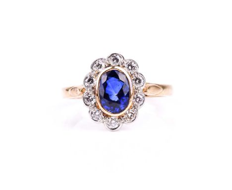 An 18ct yellow gold, diamond, and sapphire cluster ring, set with a mixed oval-cut sapphire (possibly synthetic) within a bor