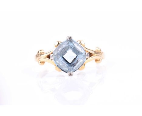 An 18ct yellow gold and aquamarine ring, set with a mixed cushion-cut aquamarine, four claw set, with stylised split shoulder