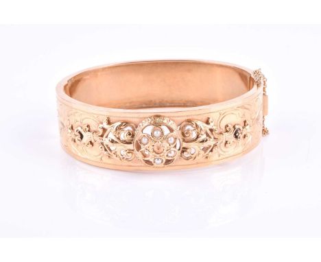 A mid 20th century French yellow metal and pearl bangle, the mount with openwork floral and repousse decoration, inset with p