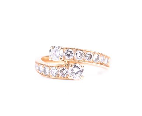 A yellow metal and diamond crossover ring, set with graduated round brilliant-cut diamonds, the two largest set to the termin