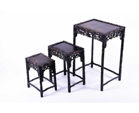 A Chinese carved hardwood nest of three occasional tables, the frames carved with prunus root decoration, with adjoining stre