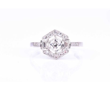 A platinum and diamond ring of hexagonal design, centred with a round brilliant-cut diamond within a hexagonal mount, the bod