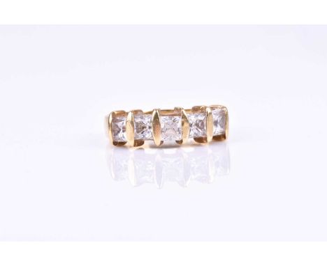 A yellow metal and CZ ring, set with five princess-cut cubic zirconias, bar-set, the yellow metal shank with indistinct marks