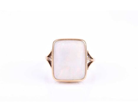 A yellow metal and opal ring, set with a bezel-set rectangular opal, measuring approximately 16 x 14 mm, the shank unmarked (