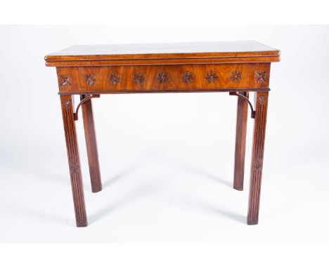 A Georgian mahogany foldover card table, the plain top opening to reveal a green baize lined interior, with flower carved fri